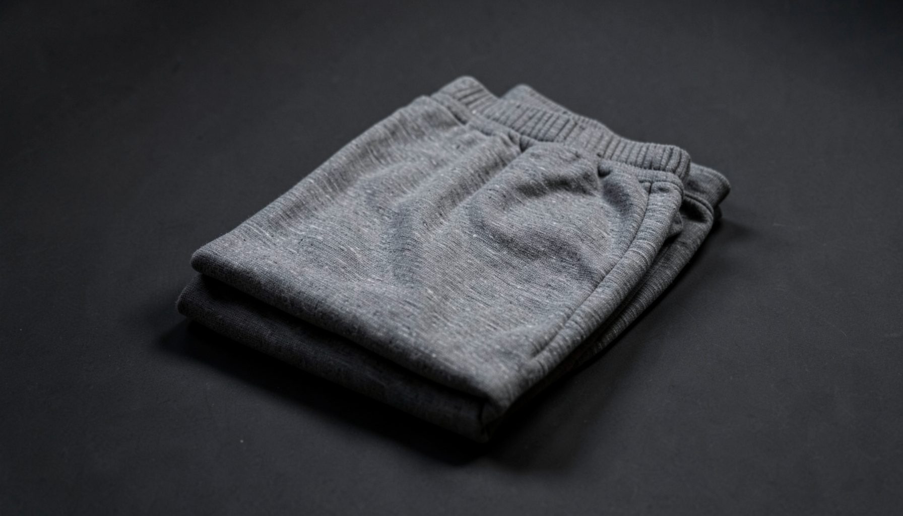 Folded gray sweatpants on dark background, calm neutral tones